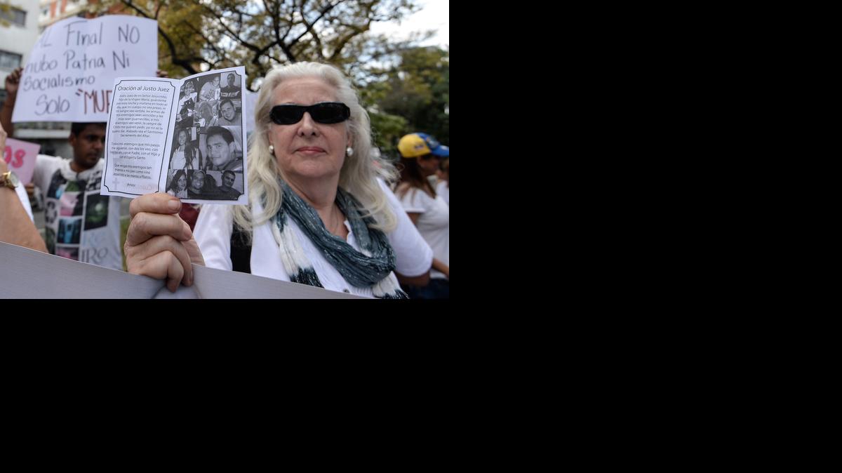 
Una mujer muestra una foto con varias personas que han muerto en protestas antigubernamentales, el miércoles en Caracas. 
