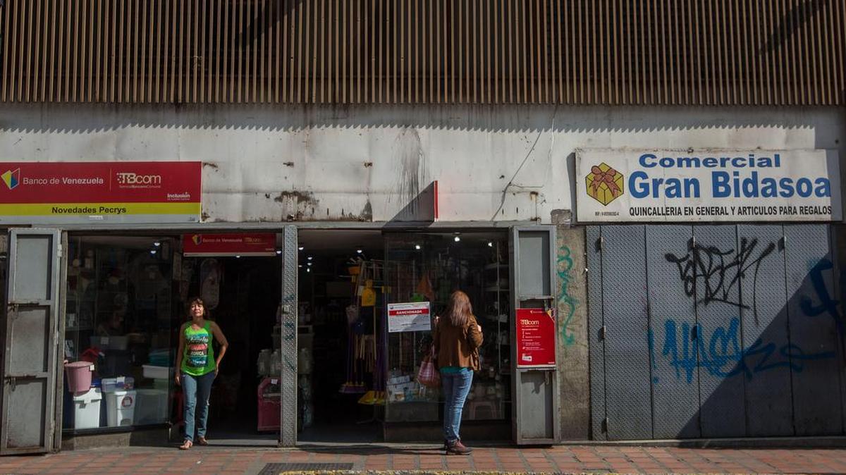 Un local comercial abierto y otro cerrado hoy, viernes 28 de octubre de 2016, en Caracas (Venezuela).