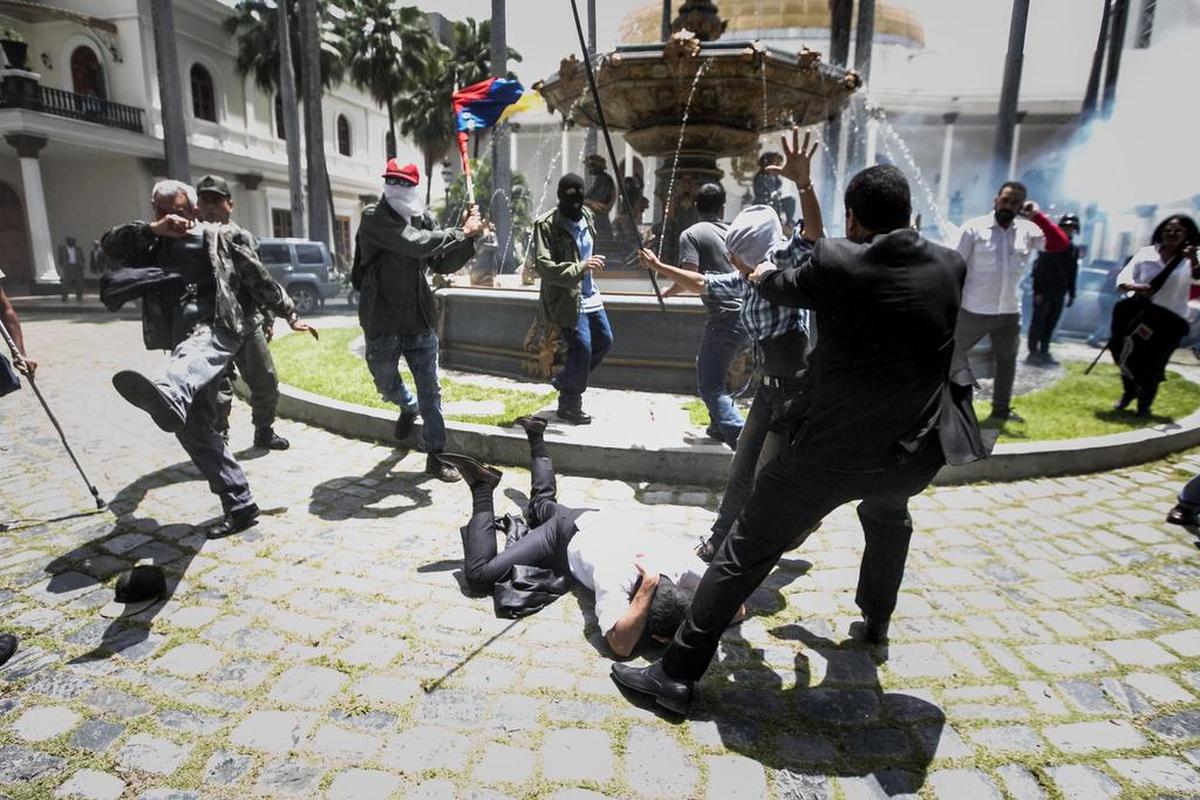 El diputado Armando Armas (c) es golpeado por manifestantes en el piso en la Asamblea Nacional el miércoles 5 de julio de 2017, en Caracas (Venezuela).