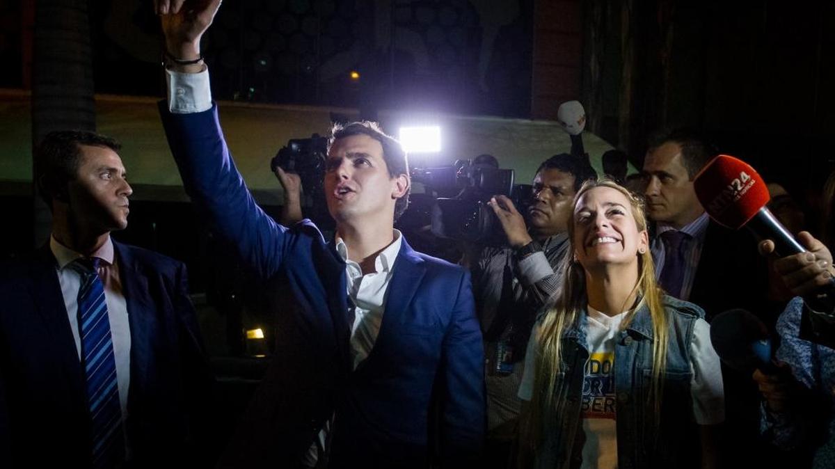 El líder del partido español Ciudadanos, Albert Rivera (i), y Lilian Tintori (d), esposa del opositor venezolano encarcelado Leopoldo López, saludan al opositor encarcelado Daniel Ceballos a las afueras de su residencia hoy, 24 de mayo de 2016, en la ciudad de Caracas (Venezuela). Rivera se vio hoy impedido de visitar a Ceballos al igual que al alcalde metropolitano de Caracas, Antonio Ledezma, que se encuentra privado de libertad en su propia casa, acusado de participar en planes para conspirar contra el Gobierno de Nicolás Maduro.