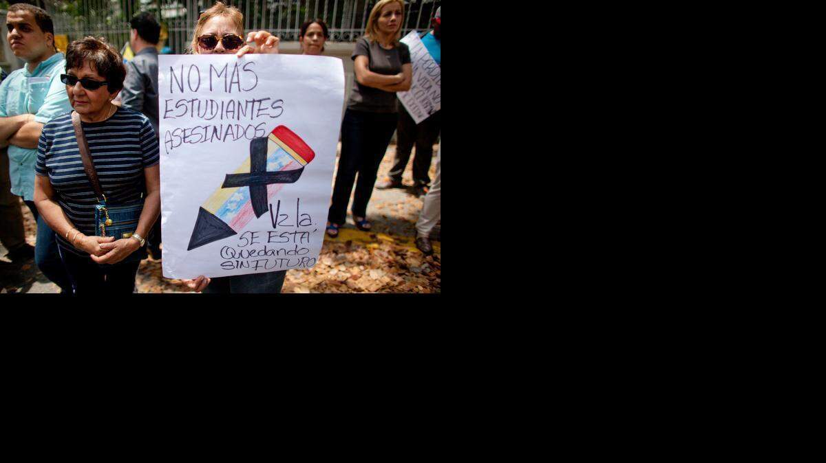 
Afuera de la misión diplomática del Vaticano en Caracas, una mujer protesta con un cartelón que denuncia la violencia represiva contra los estudiantes venezolanos. 
