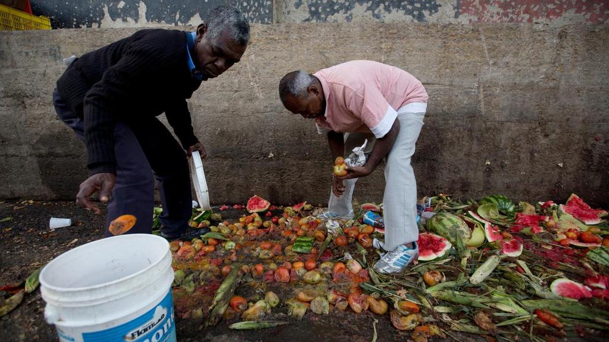 Pedro Hernández, a la izquierda, y su amigo Luis Daza recogen tomates de la basura del mercado público de Coche en Caracas, Venezuela.
