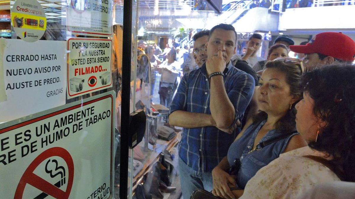 Un grupo de personas espera afuera de una tienda mientras funcionarios del gobierno ajustan los precios en una tienda en Caracas, el jueves.