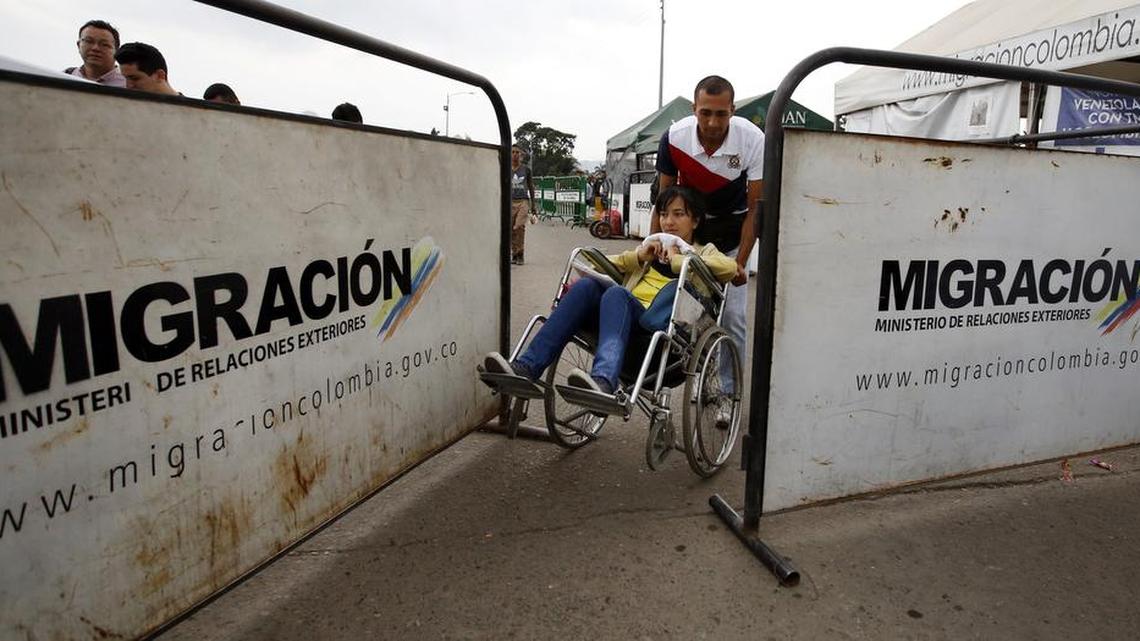 El venezolano Nelson González ayuda a su esposa Grecia Sabala, quien está en una silla de ruedas, a cruzar la frontera de regreso a Venezuela, en una imagen del 22 de febrero del 2018. Sabala regresó tras recibir tratamiento de quimioterapia en Cúcuta, Colombia. La crisis de los servicios médicos en Venezuela ya se hace sentir en Colombia, en momentos que miles de migrantes llegan con necesidad de atención médica urgente.