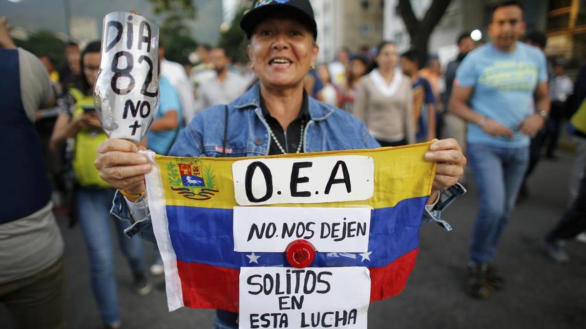 Una manifestante sostiene una bandera nacional venezolana con un mensaje para la OEA, en Caracas, Venezuela, el miércoles 21 de junio de 2017.