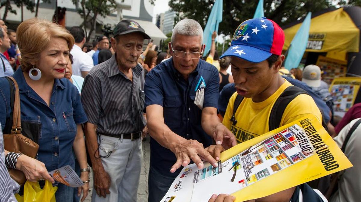 Un hombre da indicaciones de como votar por la alianza opositora venezolana Mesa de la Unidad Democrática el 11 de noviembre del 2015, en Caracas.