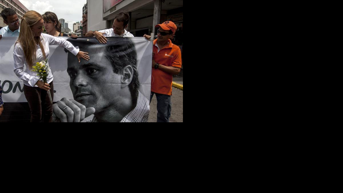 Lilian Tintori (i), esposa del dirigente de la oposición venezolana, Leopoldo López, muestra una pancarta con la imagen de éste, a las afueras del Palacio de Justicia, el martes 30 de septiembre de 2014, donde continúa el juicio penal contra López, en la ciudad de Caracas (Venezuela).
