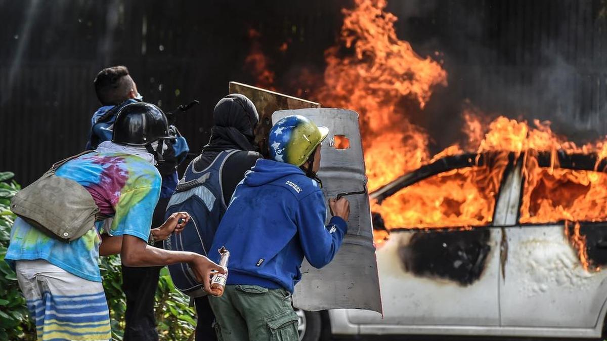 Un grupo de manifestantes se protegen con escudos de fabricación casera, durante una protesta contra el gobierno de Nicolás Maduro el jueves en la Plaza Altamira, en Caracas.