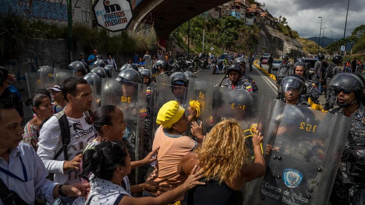 Un grupo de personas protesta frente a miembros de la Policía Nacional Bolivariana (PNB) el jueves 28 de diciembre del 2017, en Caracas (Venezuela).