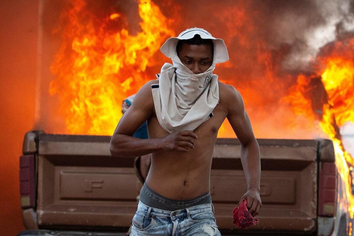 Una persona corre durante enfrentamientos entre antichavistas y miembros de la Guardia Nacional Bolivariana de Venezuela este sábado en el paso fronterizo ubicado en la localidad de Pacaraima (Brasil).