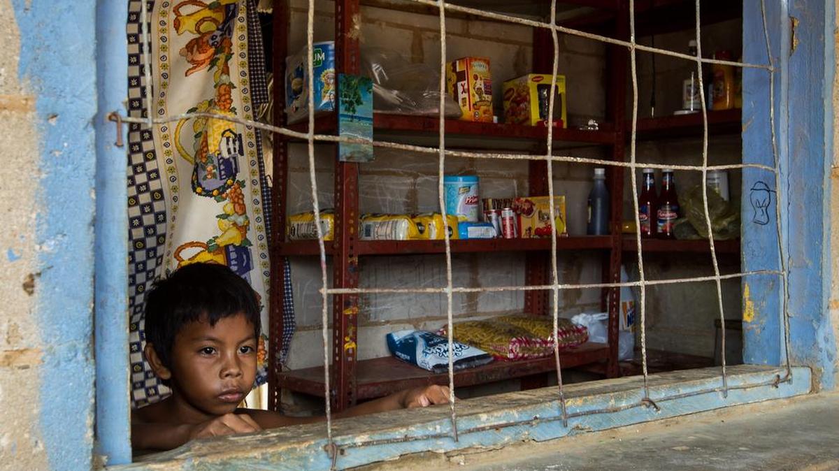 
Un niño mira desde la ventana de su casa en donde venden artículos de primera necesidad en la localidad de Canchancha en la ciudad de Maracaibo, Venezuela, el 11 de septiembre.
