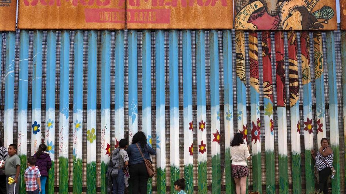 En Tijuana, unos kilómetros más lejos de la playa, partes de la barda oxidada tienen pegadas decenas de cruces de madera con el nombre de los emigrantes que murieron tratando de lograr el sueño americano: al menos uno al día, según ONG.