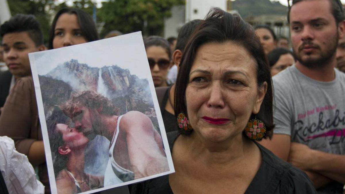 Una mujer sostiene un retrato de la ex Miss Venezuela Mónica Spear y su ex marido Henry Thomas Berry durante una protesta contra la violencia en Caracas, Venezuela, el miércoles 8 de enero de 2014.