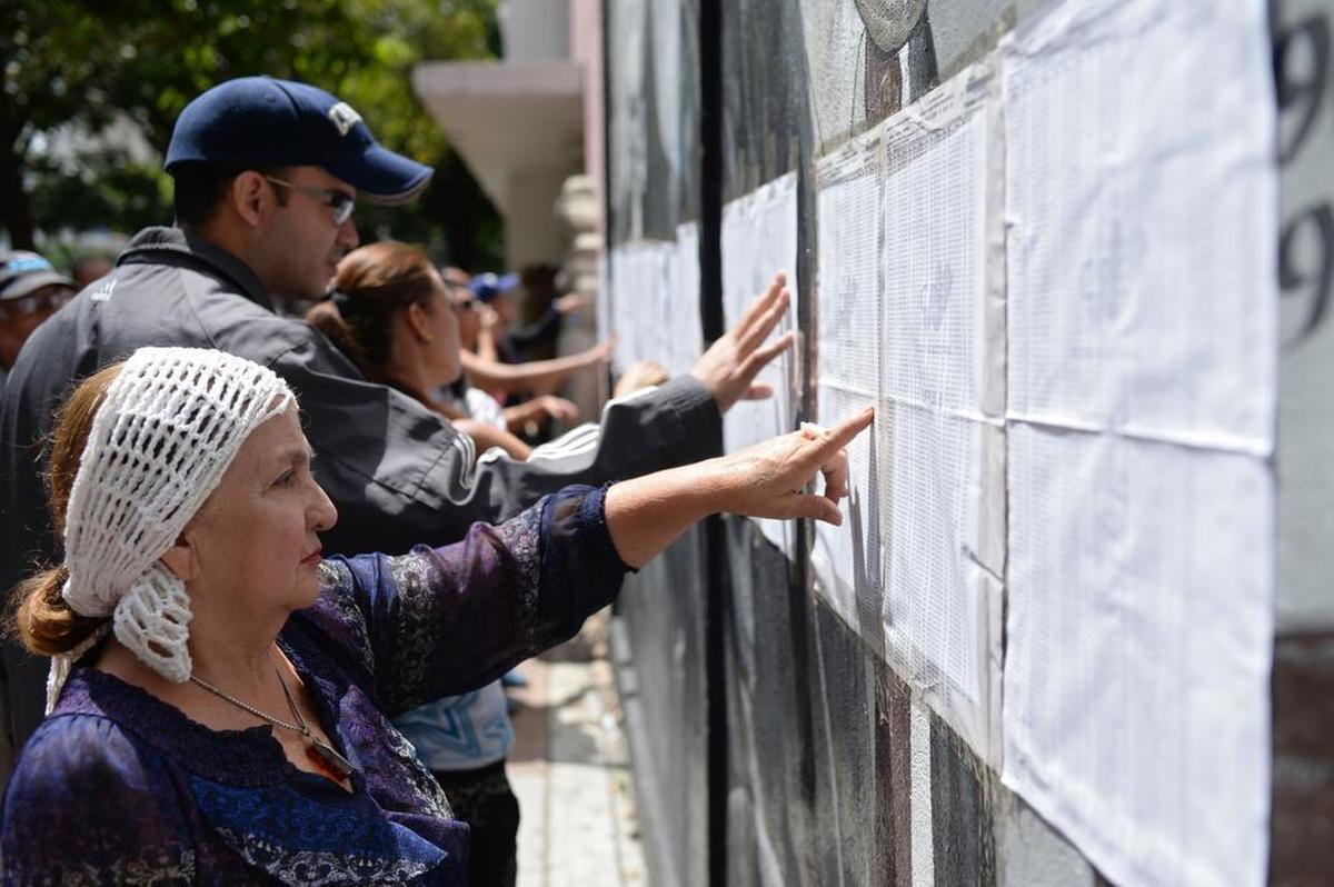 Personas revisan su nombre antes de emitir su voto para elegir una Asamblea Constituyente en Caracas el 30 de julio de 2017.