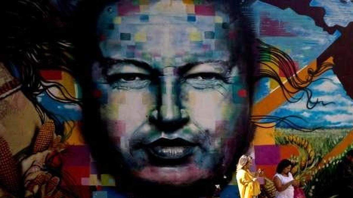 
Un par de mujeres se resguarda del sol junto a un enorme mural en honor a Hugo Chávez en el barrio 23 de enero de Caracas, en esta foto de archivo de julio del 2014.
