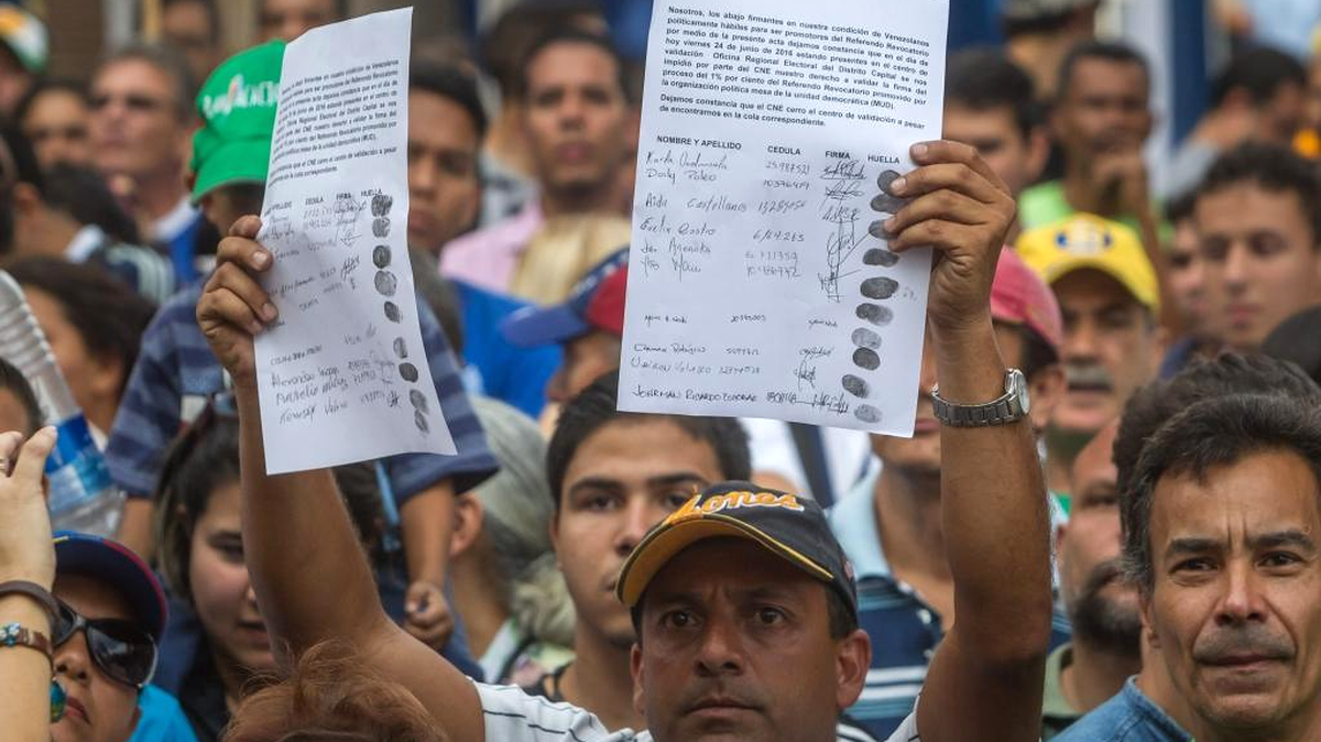 Un hombre enseña una constancia hecha por personas que no pudieron validar sus firmas y datos personales luego de cerrar un centro de validación del Consejo Nacional Electoral (CNE) el viernes 24 de junio de 2016, en Caracas (Venezuela).