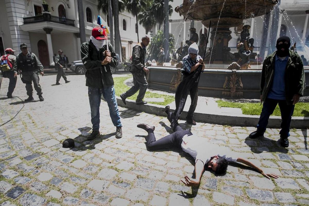 El diputado Armando Armas (c) permanece en el suelo tras ser golpeado por manifestantes en la Asamblea Nacional el miércoles 5 de julio de 2017, en Caracas (Venezuela).