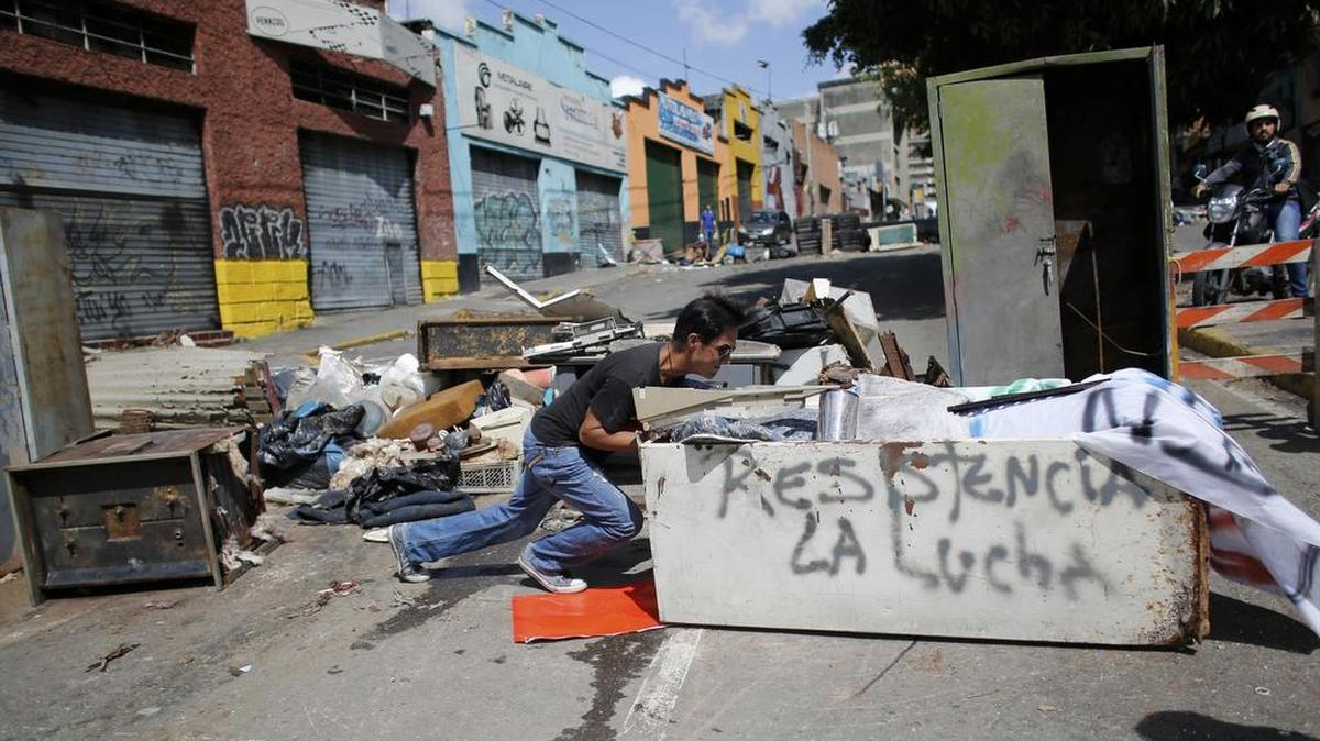 Un manifestante fabrica una barricada para protestar contra el plan del presidente Nicolás Maduro de reescribir la constitución en Caracas, Venezuela, el sábado 29 de julio de 2017.