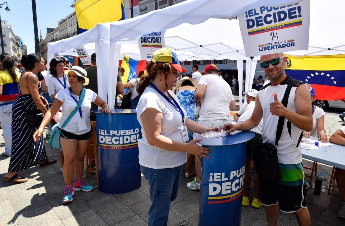 Una residente venezolana en Madrid coloca su voto en una mesa de votación durante un plebiscito celebrado en la Puerta del Sol de Madrid el 16 de julio de 2017 .