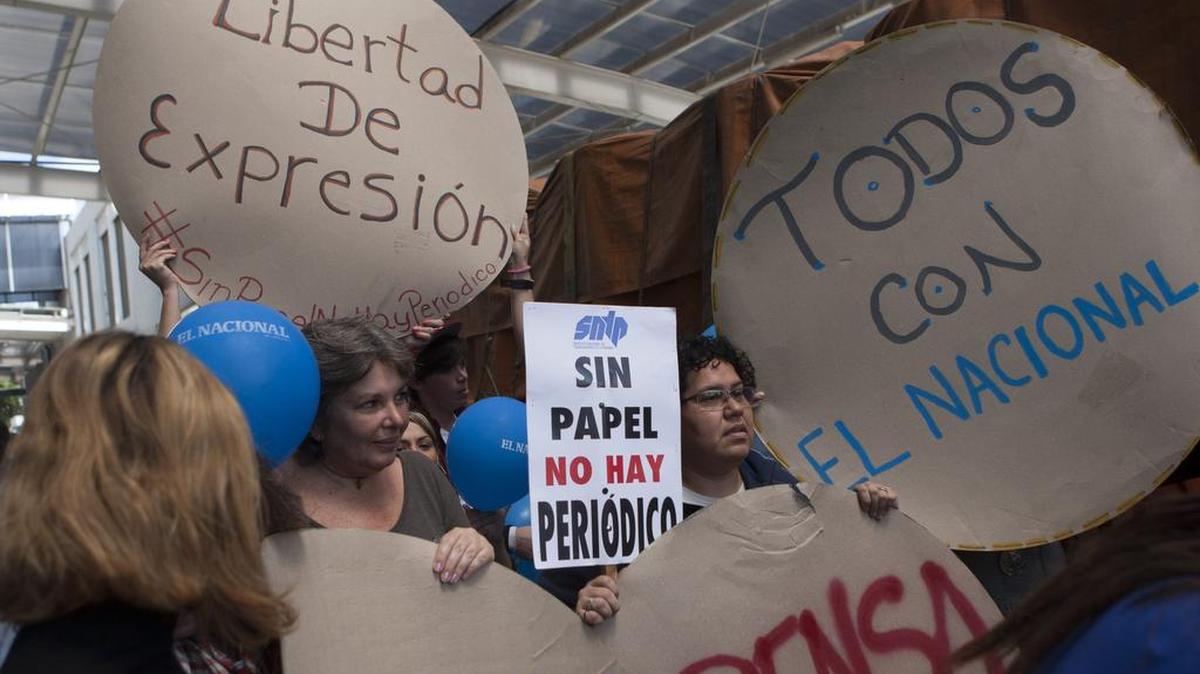 Trabajadores del diario El Nacional reciben con anuncios el cargamento con el papel periódico proveniente de Colombia, el viernes 11 de abril del 2014, en Caracas.