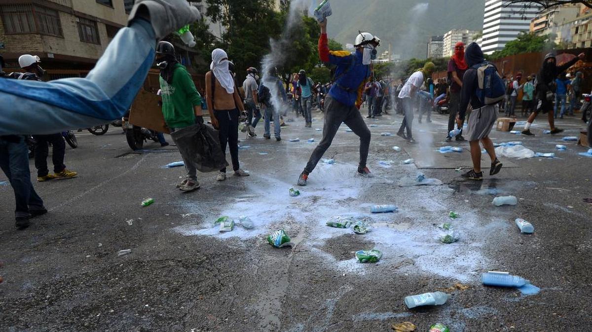 Manifestantes vacían botellas durante un choque con la policía en Caracas, el 24 de mayo.