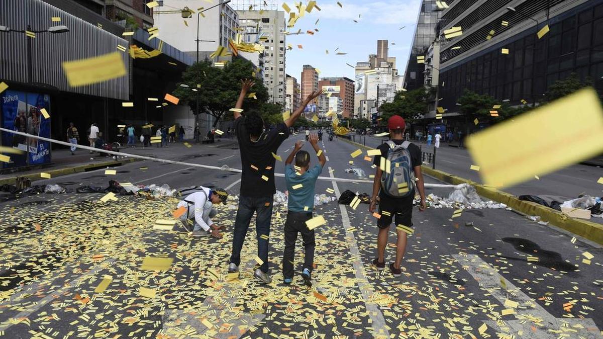 Un grupo de jóvenes lanzan a la calle boletos del metro durante el paro cívico convocado por la oposición venezolana el jueves 20 de julio de 2017, en Caracas, Venezuela.