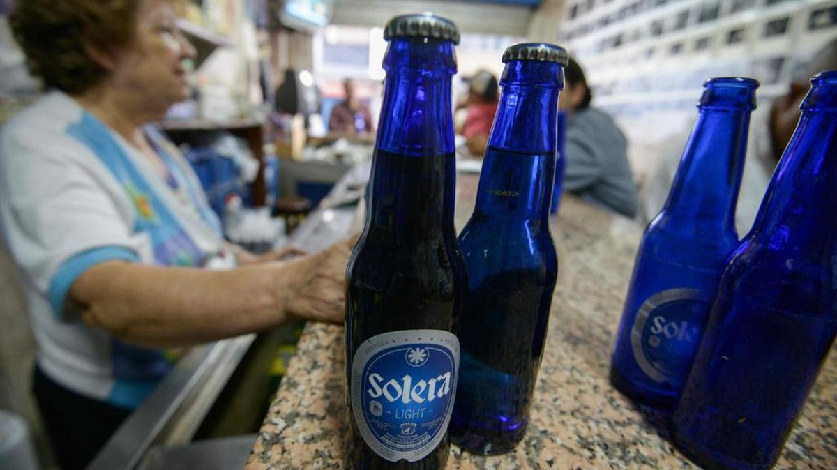 Una mujer vende cerveza producida en la cervecería Polar, en un bar en Caracas el 4 de mayo de 2016. La mayor cervecera del país, Polar, detuvo la producción en cuatro fábricas de cerveza el sábado pasado, diciendo que se había quedado sin la cebada, ya que no puede tener acceso a dólares para pagarle a los importadores bajo el control de cambios ajustados de Venezuela. La cervecería es parte de la corporación más grande de Venezuela, Empresas Polar, cuyo director ejecutivo, Lorenzo Mendoza, ha chocado repetidamente con Maduro.