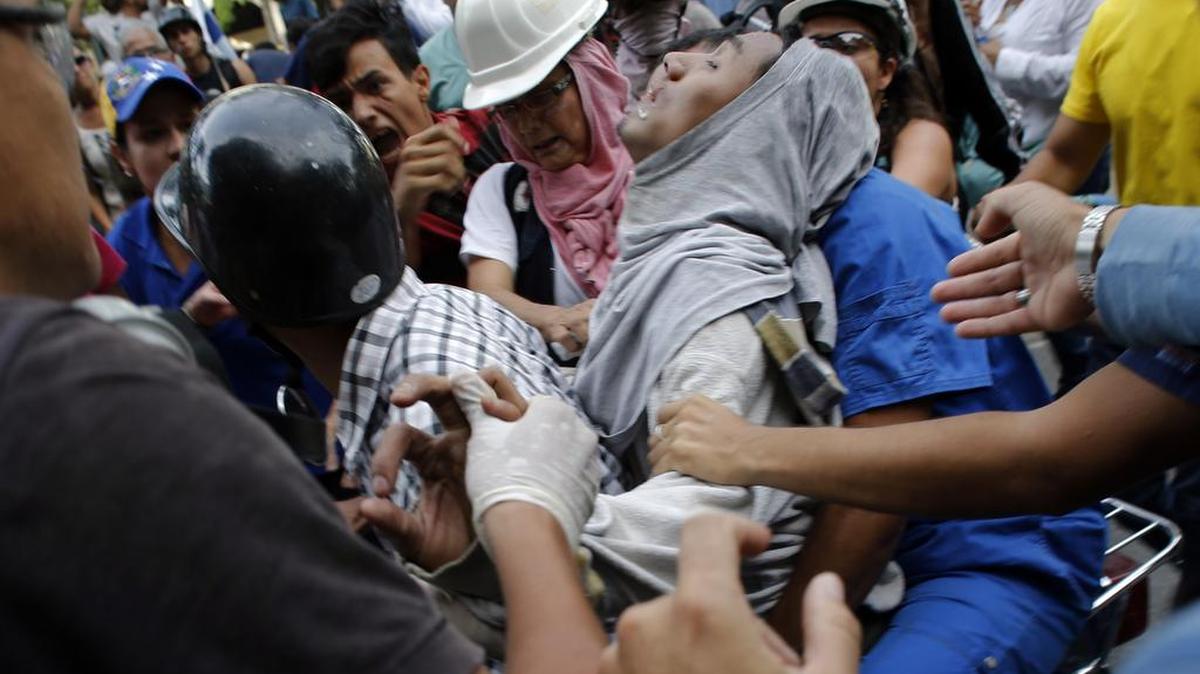 Manifestantes auxilian a un participante herido en las protestas del miércoles en Caracas que ya se extienden por unos dos meses.
