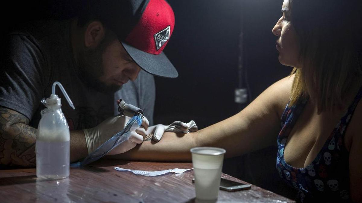 Un tatuador hace un tatuaje el domingo 2 de octubre del 2016, en Caracas (Venezuela). Un conjunto de profesionales del "arte corporal" ofrecen hacer tatuajes a cambio de donaciones de útiles escolares para que niños de bajos recursos económicos puedan comenzar el venidero año académico, esto a través de la jornada llamada "Tatuajes x útiles" que se lleva a cabo en Caracas.