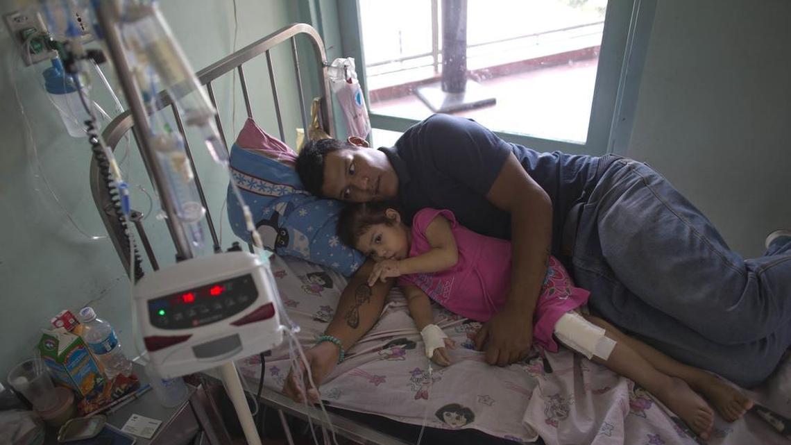Un padre descansa junto a su hija pequeña en el Hospital Universitario de Caracas.
