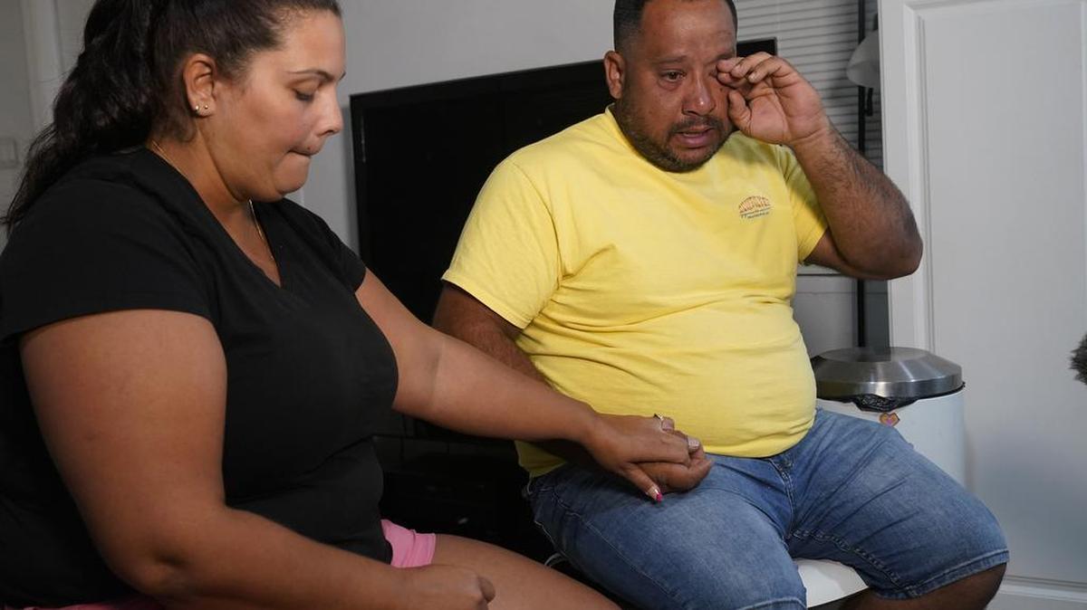 Ana Merino toma la mano de su esposo, Víctor Macedo, mientras recuerda las amenazas de muerte que recibieron en Venezuela por ser opositores políticos del gobierno socialista, el miércoles 27 de septiembre de 2023 en Davie, Florida. La familia Macedo cruzó la frontera sur de Estados Unidos hace casi dos años y recientemente calificó para un estatus legal temporal.