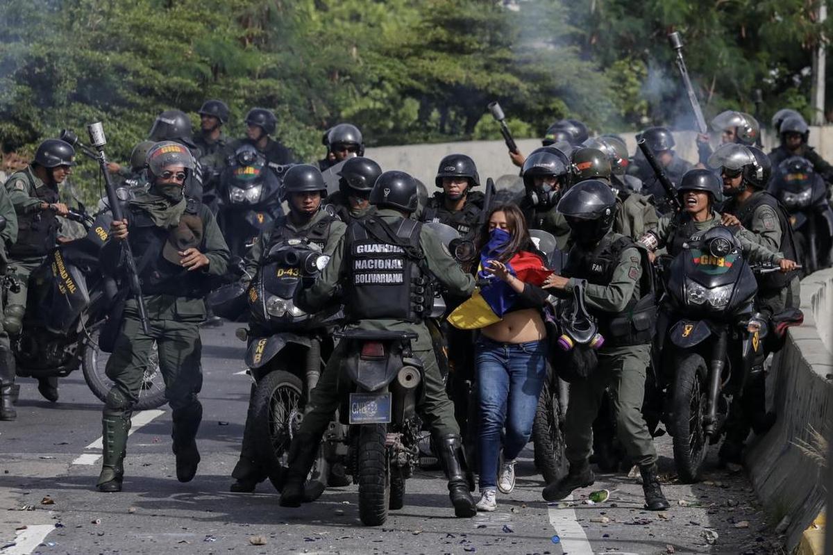 Una joven manifestante es rodeada por una orda de motorizados de la Guardia Nacional Bolivariana el lunes en Caracas, Venezuela. Los opositores venezolanos atendieron a la convocatoria de realizar un “trancazo” de calles en todo el país contra la “dictadura” de Nicolás Maduro.