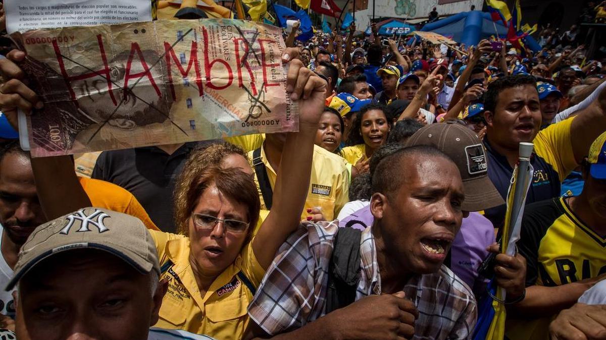 Una manifestante sostiene un letrero con la palabra “Hambre” durante una protesta contra el gobierno venezolano, este sábado 14 de mayo en Caracas. Centenares de opositores se concentraron en la capital para exigir a las autoridades electorales que den celeridad a la solicitud de la activación de un referendo revocatorio que permita terminar con el mandato del presidente Nicolás Maduro.