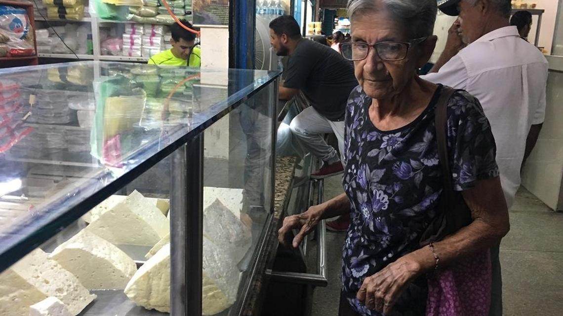 Maritza Díaz, una ama de casa de 72 años, está triste sobre los precios de los productos que se exhiben en la vidriera de un local del mercado de La Limpia en Maracaibo, en el occidente de Venezuela.