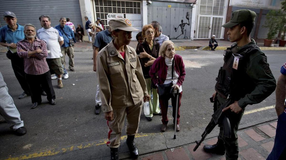 Votantes flanqueados por soldados de la Guardia Nacional Bolivariana esperan ingresar a una estación de votación en Caracas, Venezuela, el domingo 10 de diciembre de 2017.
