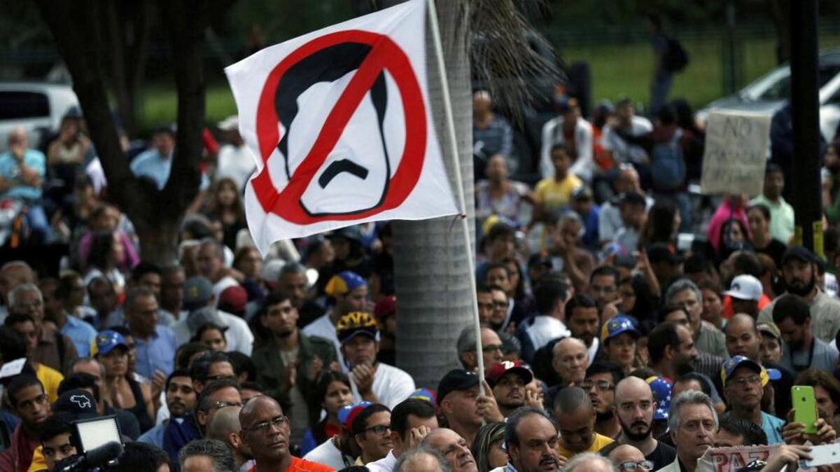 Manifestantes antigubernamentales ondean una bandera de rechazo al gobernante Nicolás Maduro este lunes en Caracas.
