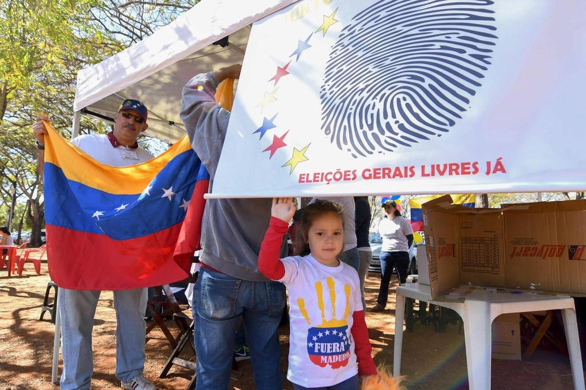 Una chica con una camiseta que lee "Fuera Maduro" acompaña a su madre, una venezolana que vive en Brasil, durante un plebiscito en el Parque Sarah Kubitschek en Brasilia, el 16 de julio de 2017.