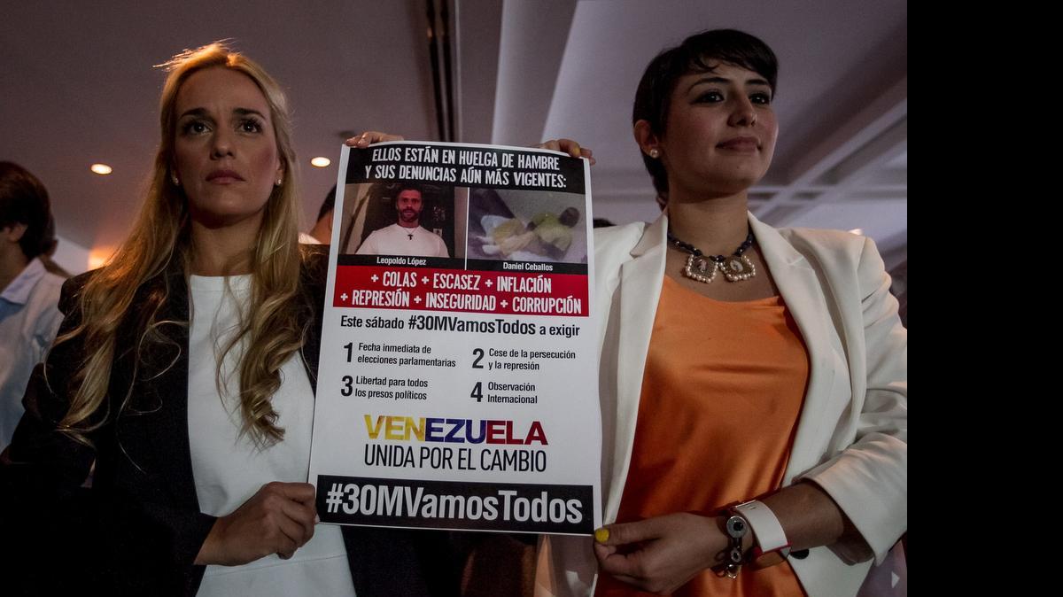 
La alcaldesa del municipio venezolano San Cristóbal y esposa del preso político Daniel Ceballos, Patricia de Ceballos (der.), sostiene un cartel con la esposa del opositor preso Leopoldo López, Lilian TIntori, durante una rueda de prensa el miércoles en Caracas. 
