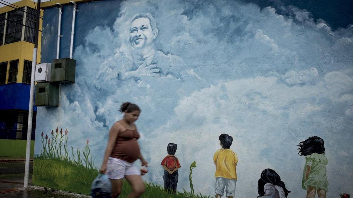 Una mujer embarazada camina frente a un mural de Hugo Chávez en Sabaneta, Venezuela, en octubre del 2015.