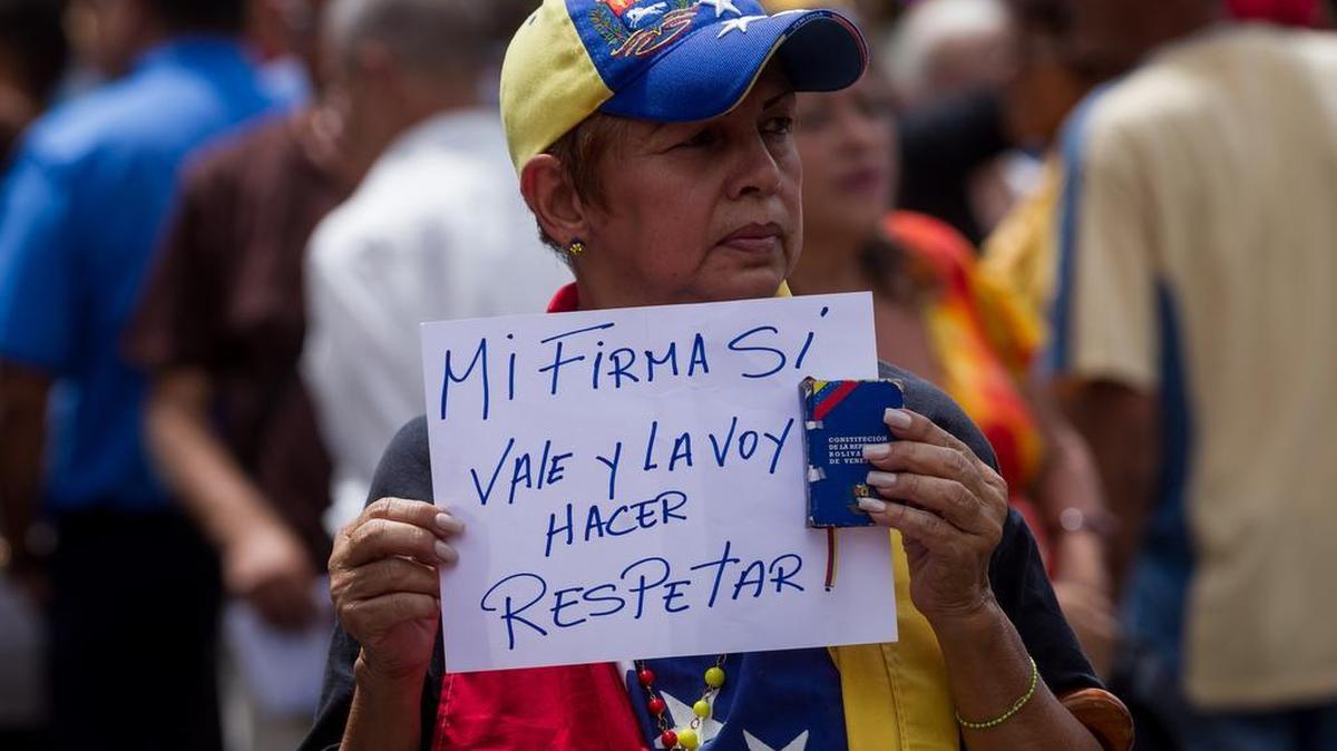 Una mujer sostiene un letrero durante una manifestación de la oposición en apoyo de la revocatoria del mandato del presidente Nicolás Maduro el 6 de junio de 2016, en la ciudad de Caracas (Venezuela).