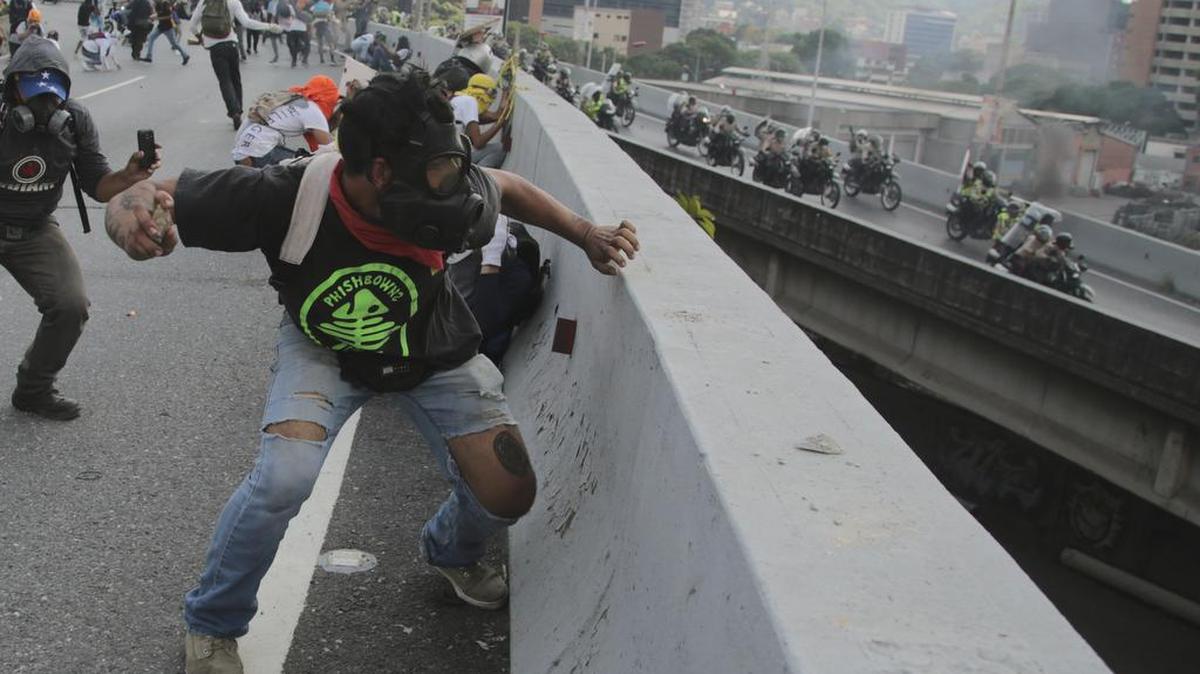 Manifestantes contra el gobierno de Nicolás Maduro lanzan piedras desde un paso elevado de la autopista a una patrulla de la policía en Caracas, Venezuela, el lunes 24 de abril de 2017.