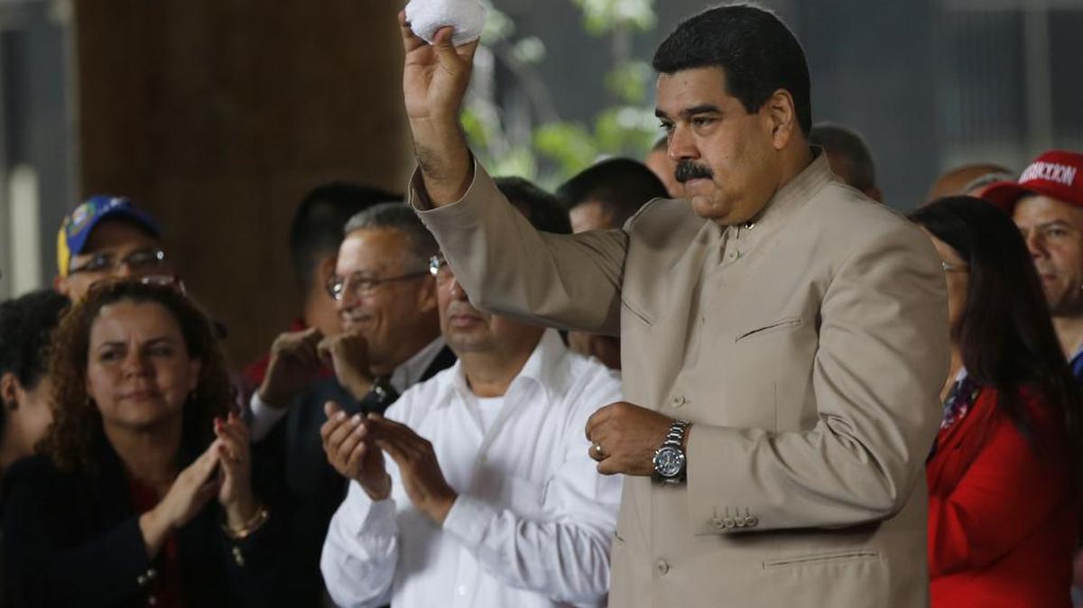 El presidente venezolano, Nicolás Maduro, arroja una toalla a los simpatizantes después de limpiar su rostro afuera de la sede del Consejo Nacional Electoral (CNE) en Caracas, Venezuela, el miércoles 3 de mayo de 2017.