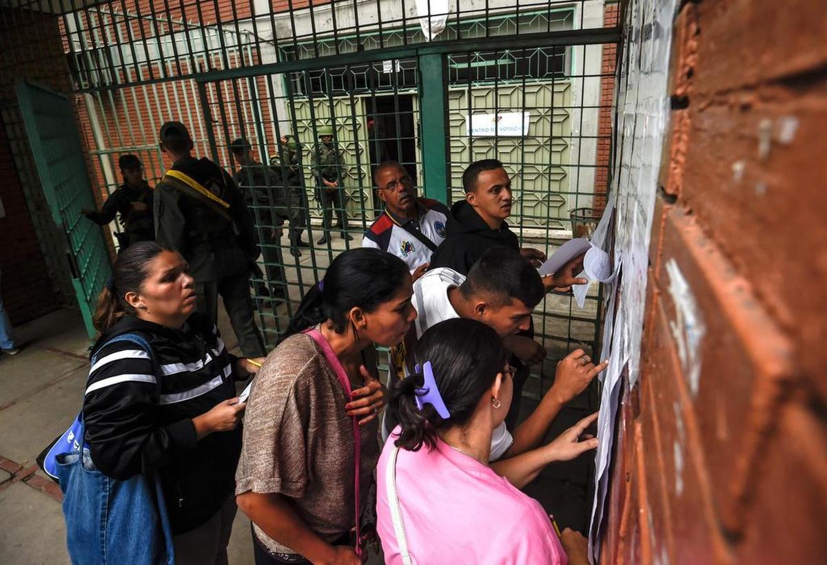 Personas revisan su nombre antes de emitir su voto para elegir una Asamblea Constituyente en Caracas el 30 de julio de 2017.
