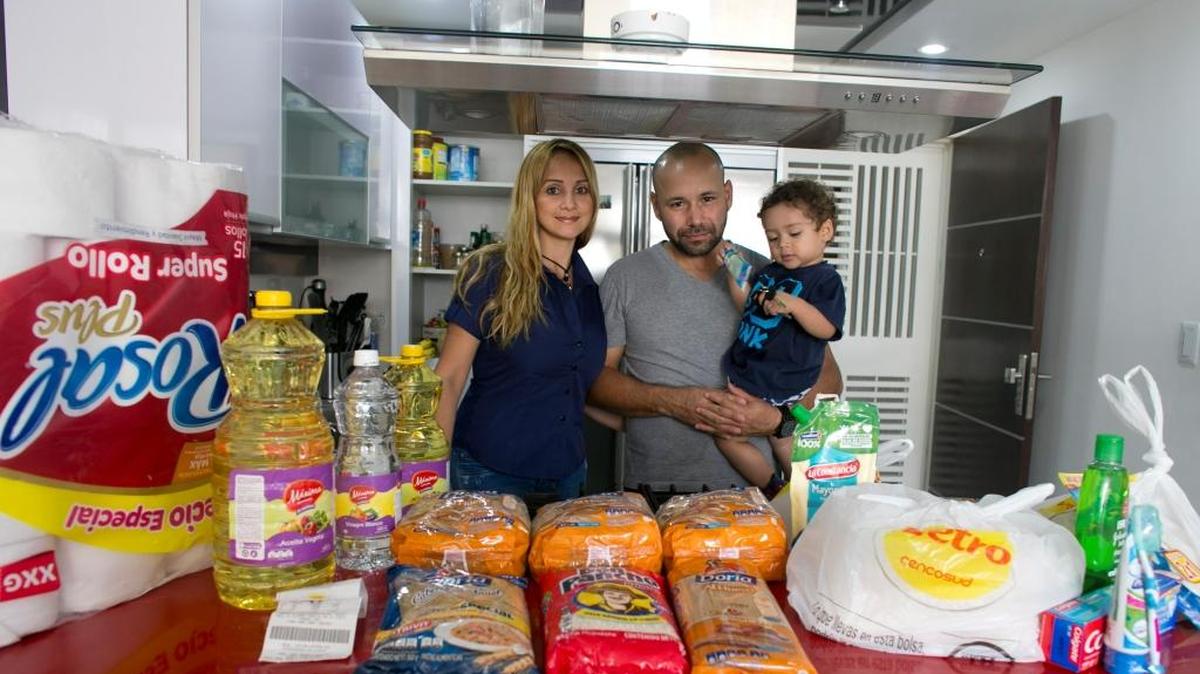 Tebie González y Ramiro Ramírez, con su hijo de dos años, Sebastián, muestran los víveres que compraron en Colombia.