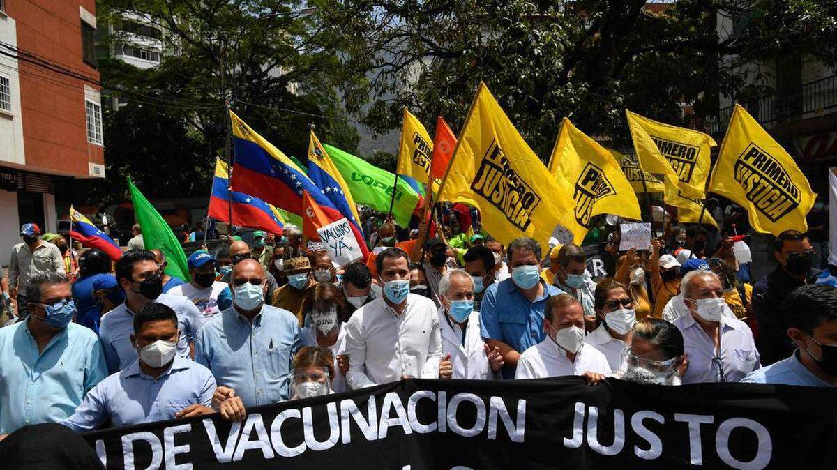 El presidente interino venezolano Juan Guaido, centro, asiste a una protesta para exigir que todos los trabajadores de la salud sean vacunados contra el COVID-19, en la plaza Los Palos Grandes en Caracas, el 17 de abril del 2021.