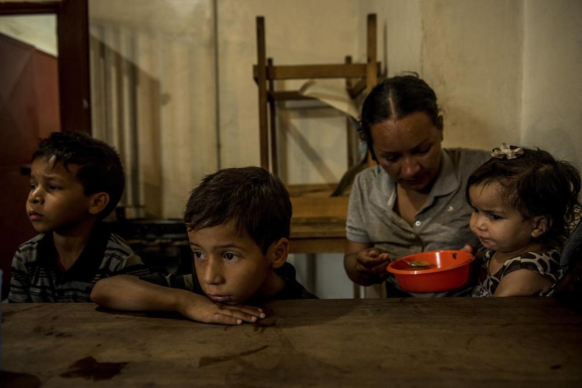 Orianna Caraballo dándole de comer a Brayner, Rayman y Sofía, sus hijos, en una cocina comunitaria en Los Teques, en septiembre.