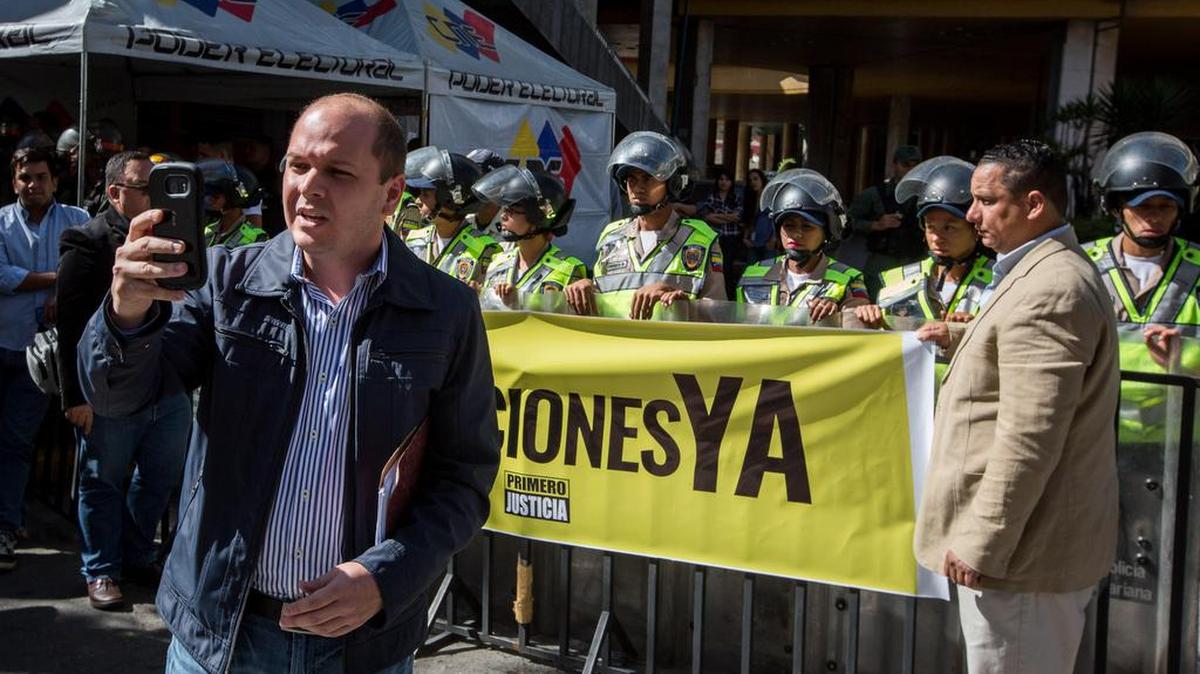 El diputado de la coalición opositora Mesa de la Unidad Democrática (MUD) Ángel Medina (c) graba con su celular la entrada del Consejo Nacional Electoral (CNE) que es custodiado por miembros de la Guardia Nacional Bolivariana (GNB) el 2 de febrero de 2017, en la ciudad de Caracas (Venezuela).