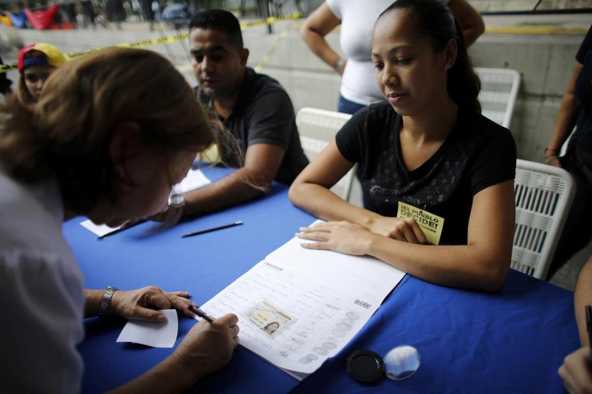 Una mujer firma el registro de votantes antes de emitir su voto en una estación electoral durante un referéndum simbólico en Caracas, Venezuela, el domingo 16 de julio de 2017.