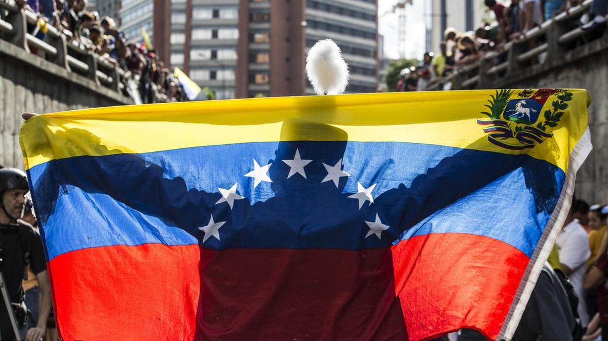 Una persona extiende una bandera venezolana ante decenas de manifestantes durante una protesta antigubernamental el lunes 24 de julio de 2017, en Caracas (Venezuela).