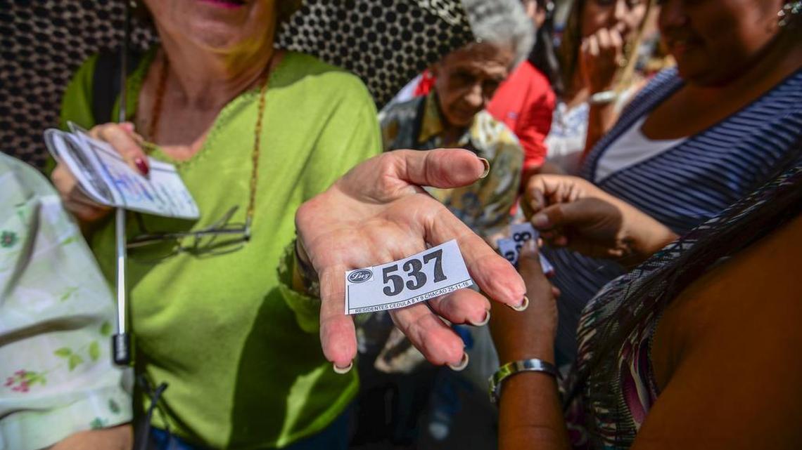 Una mujer enseña el turno que le dieron en la larga cola para comprar en un supermercado de Caracas.